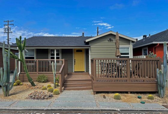 Green Bungalow with wood front deck and yellow door