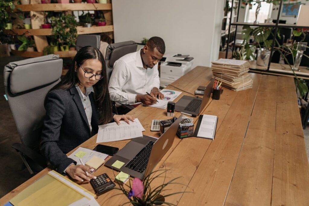 People in a Table Reading Paperwork and Using a Calculator