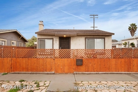 Tan stucco bungalow at 3675 Meade Avenue in Normal Heights, San Diego, featuring a high wooden privacy fence with lattice detailing and a stone-paved sidewalk.