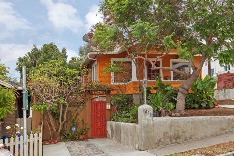 Bright orange Craftsman-style home at 2625-2627 E Street in Golden Hill with white trim, a red wooden gate, and lush tropical landscaping.
